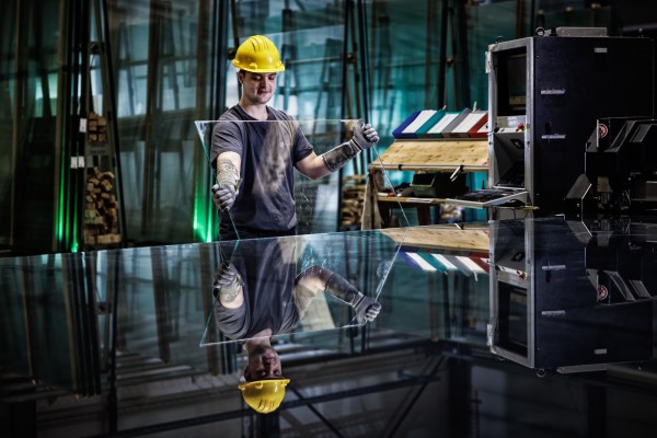 Industriefotografie zeigt Mitarbeiter beim Begutachten einer Glasplatte.