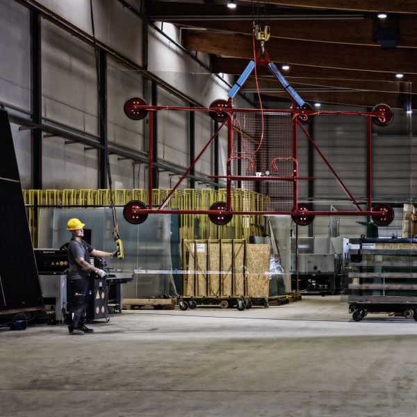 Industriefotografie zeigt Mitarbeiter beim sicheren Transport einer grossen Glasplatte.