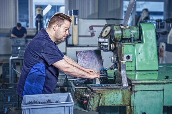 Industriefotografie zeigt Mitarbeiter bei der Präzisionsarbeit an Serieteilen.