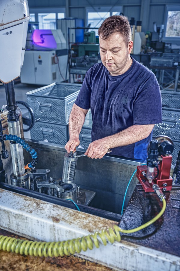 Industriefotografie zeigt Mitarbeiter bei der Präzisionsarbeit an Serieteilen.