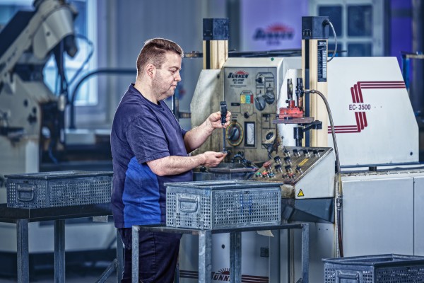 Industriefotografie zeigt Mitarbeiter bei der Präzisionsarbeit an Serieteilen.