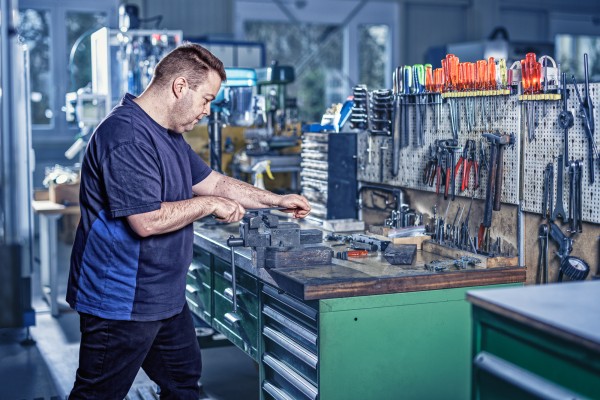 Industriefotografie zeigt Mitarbeiter beim Feilen einer Stahlplatte.